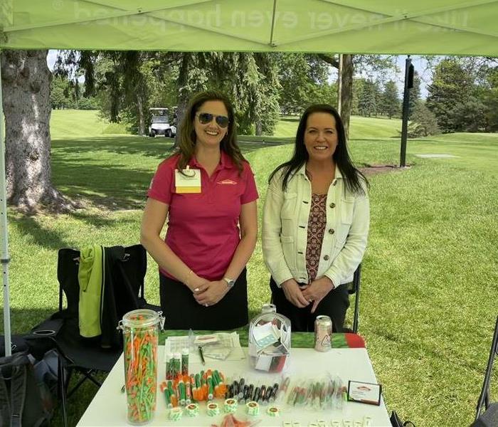 Aimee and Stephanie standing in front of a table at a golf tournament